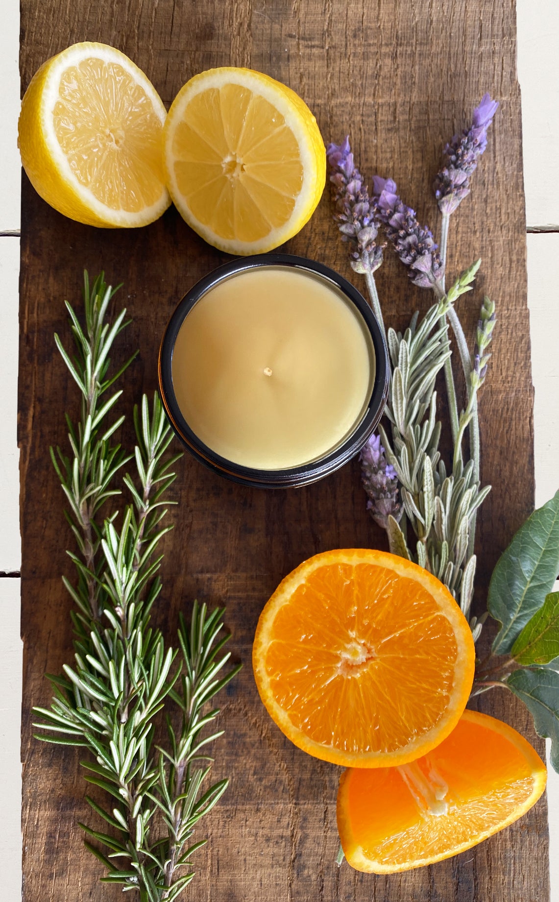 Bouclé soy candle on board surrounded by the natural ingredients. Made using lavender, rosemary, orange and lemon essential oils in East London and Brighton in the UK