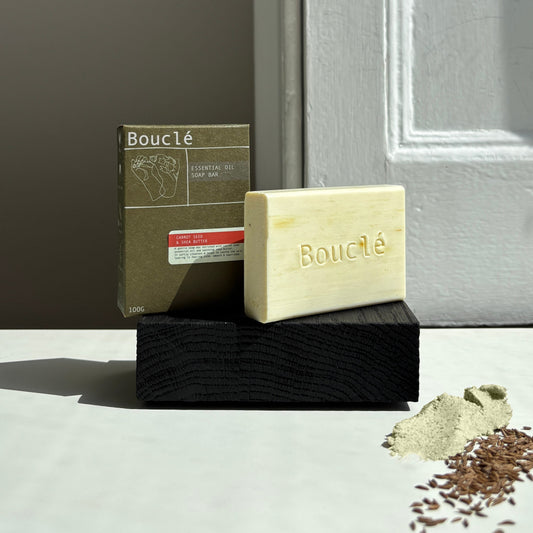 Boucle soap bar and packaging on a wooden block with a neutral background