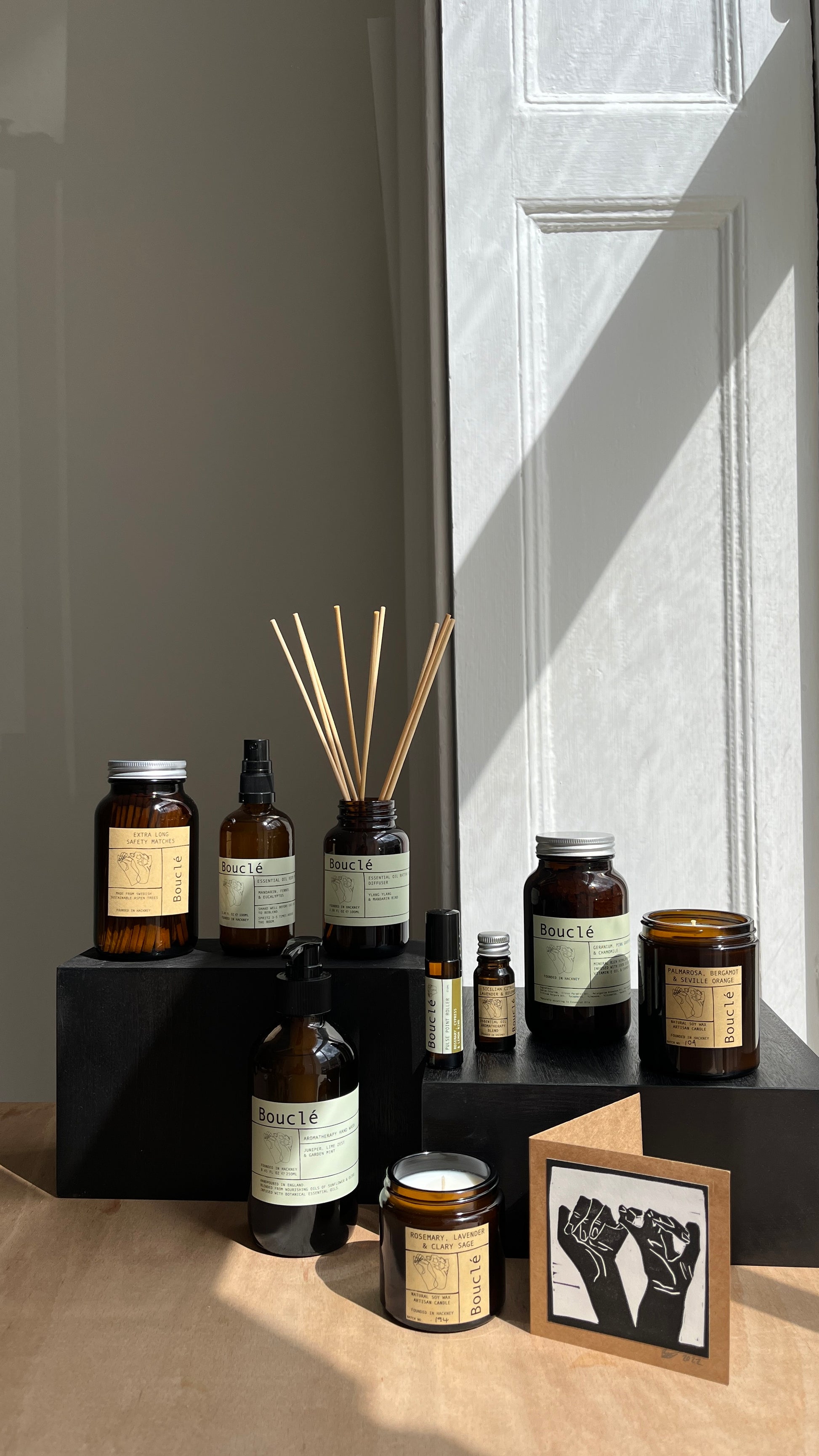 Multi-product display of Bouclé natural home fragrances including candles and room sprays.