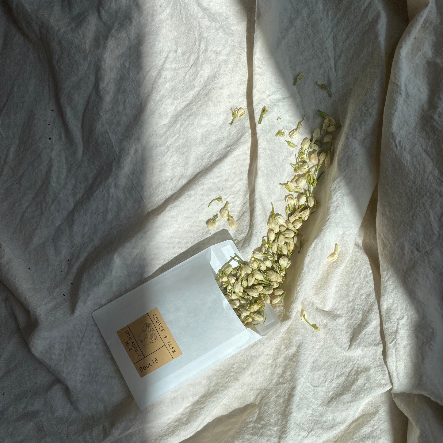 Dried botanical real petal confetti bespoke wedding pouches. This glassing plastic free pouch contains dried white jasmine buds for wedding styling.