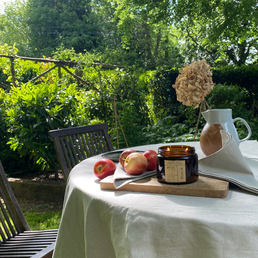 Bouclé London soy wax summer candle lit on a garden styled dinner table with lavender, rosemary, orange & citrus essential oils