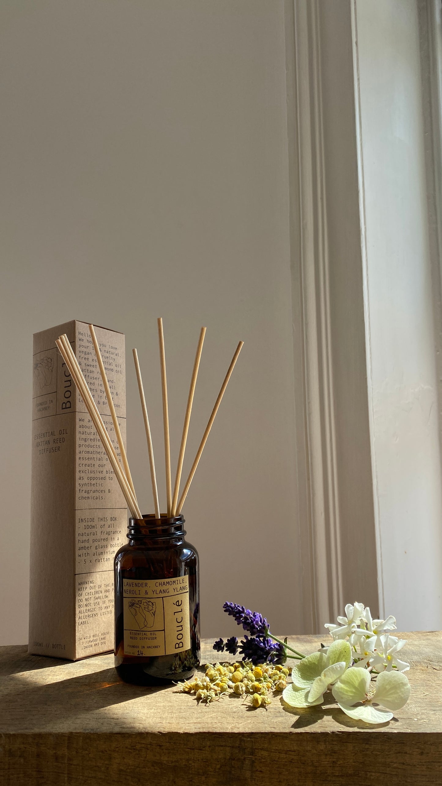 Boucle London stick reed diffuser in amber glass jar. The relaxing sleep diffuser is surrounded by it's ingredients including lavender, neroli, chamomile and ylang ylang.