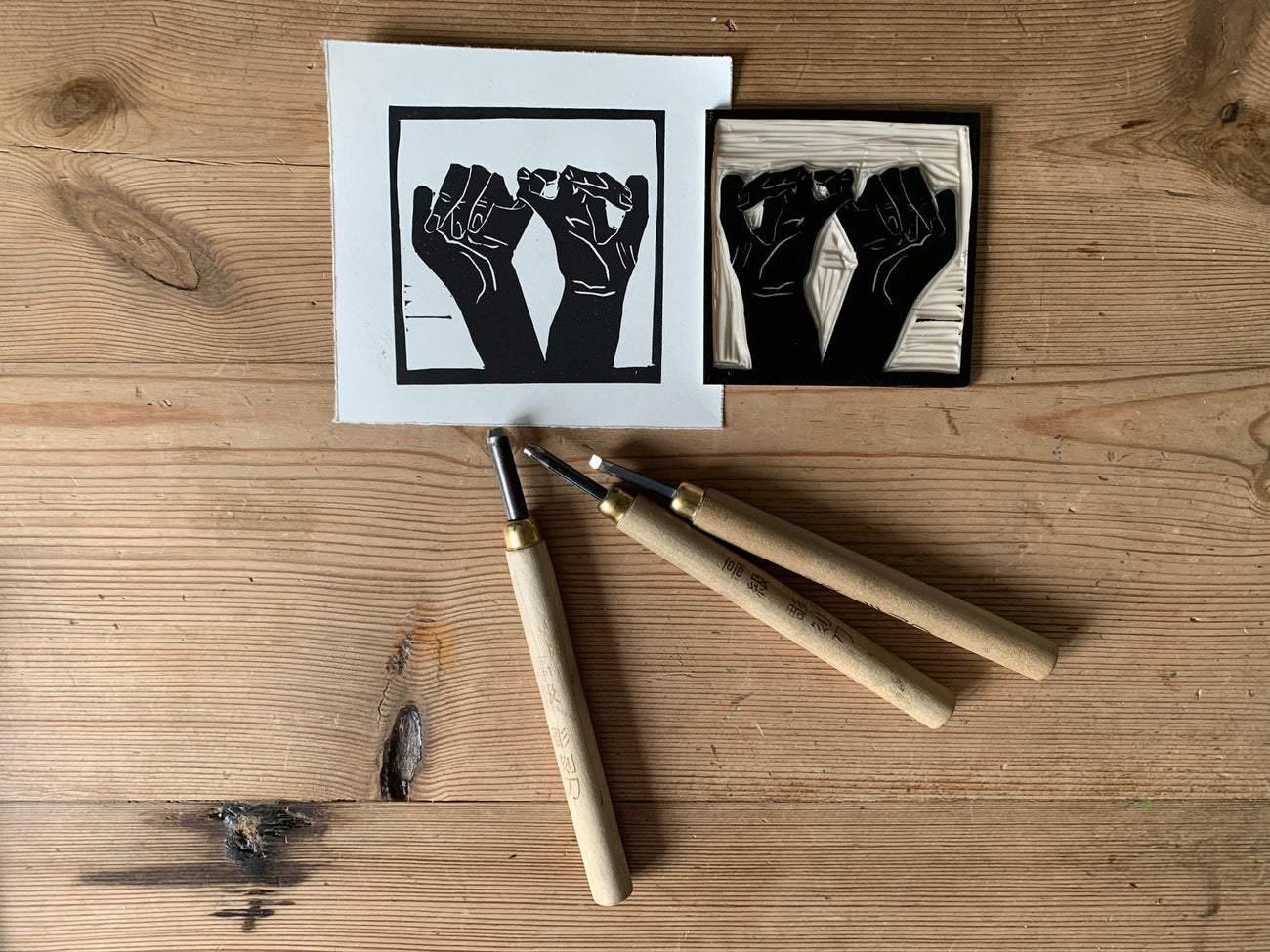 Hand printed lino print of Interlocked hands process image of the hand carve.