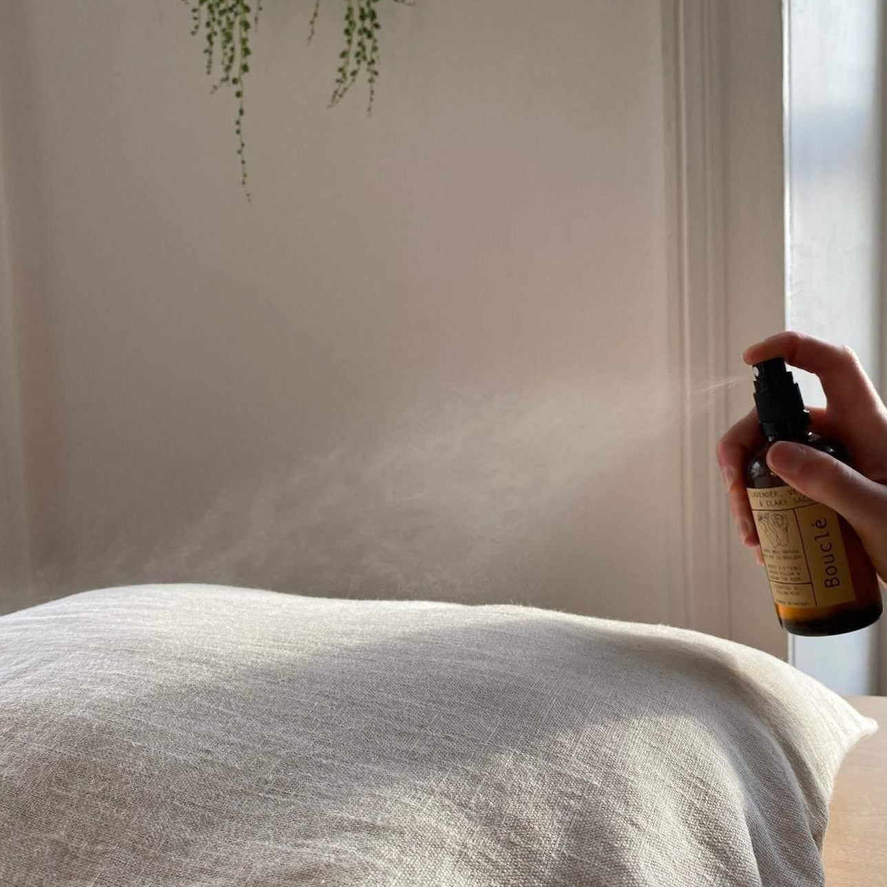 London linen spray being spritzed across pillow as natural sleep aid.