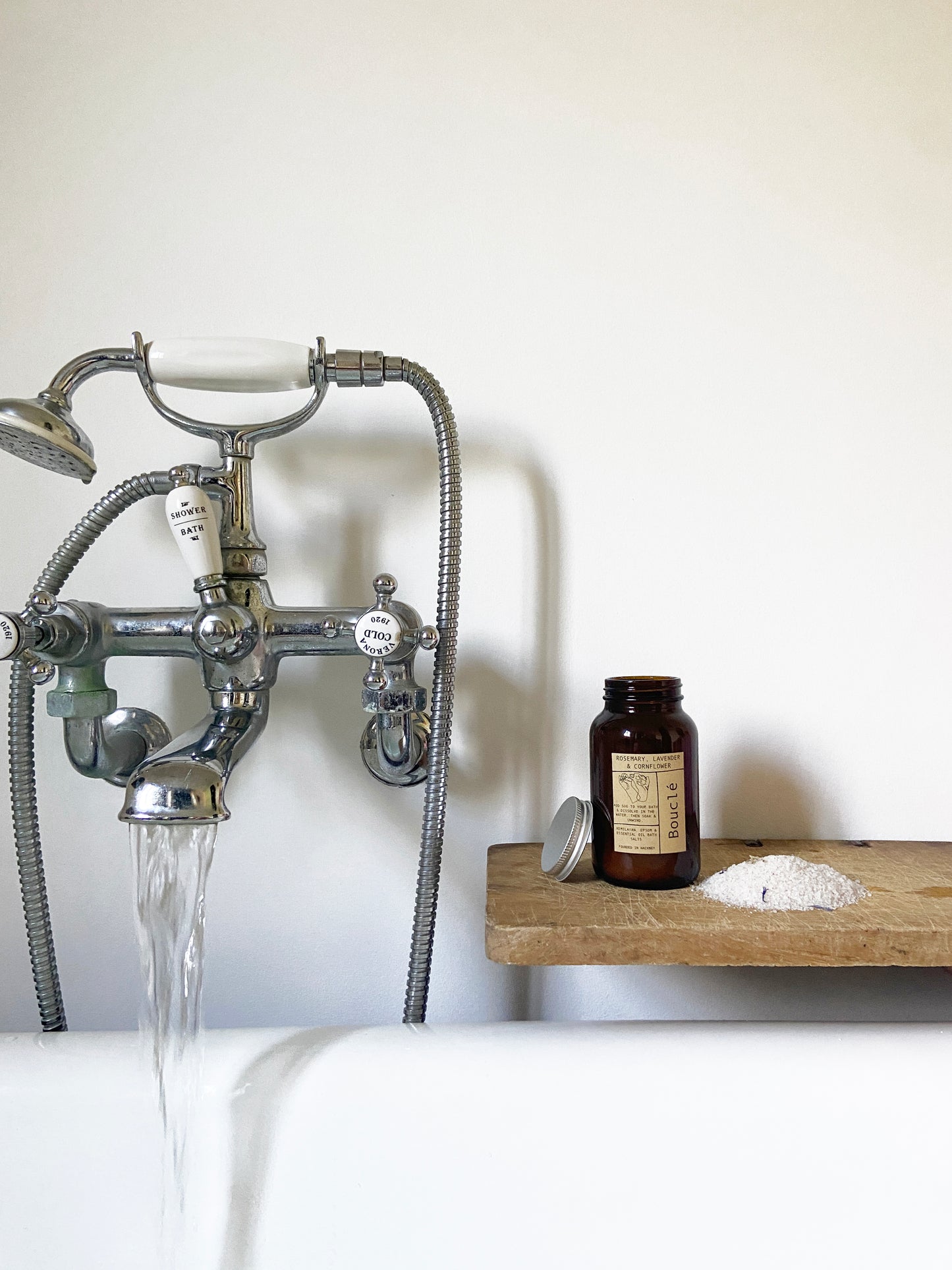 Natural and essential oil bath soak beside a roll top bath packed with essential oils and minerals for relaxing and unwinding