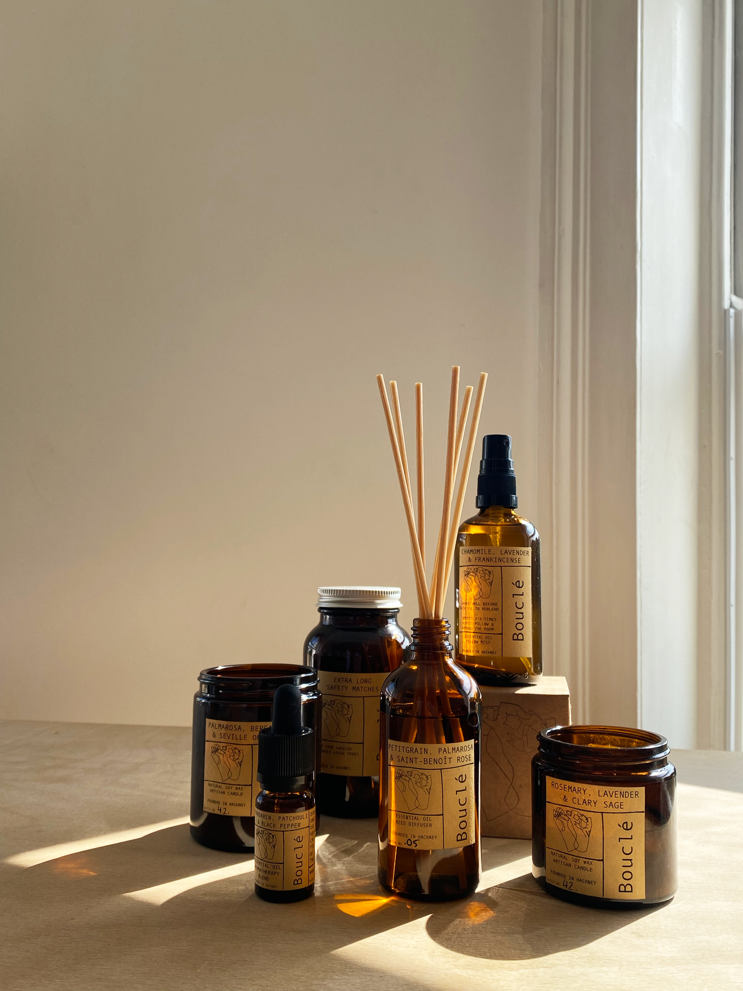 Collection of essential home fragrance products in amber glass vessels.