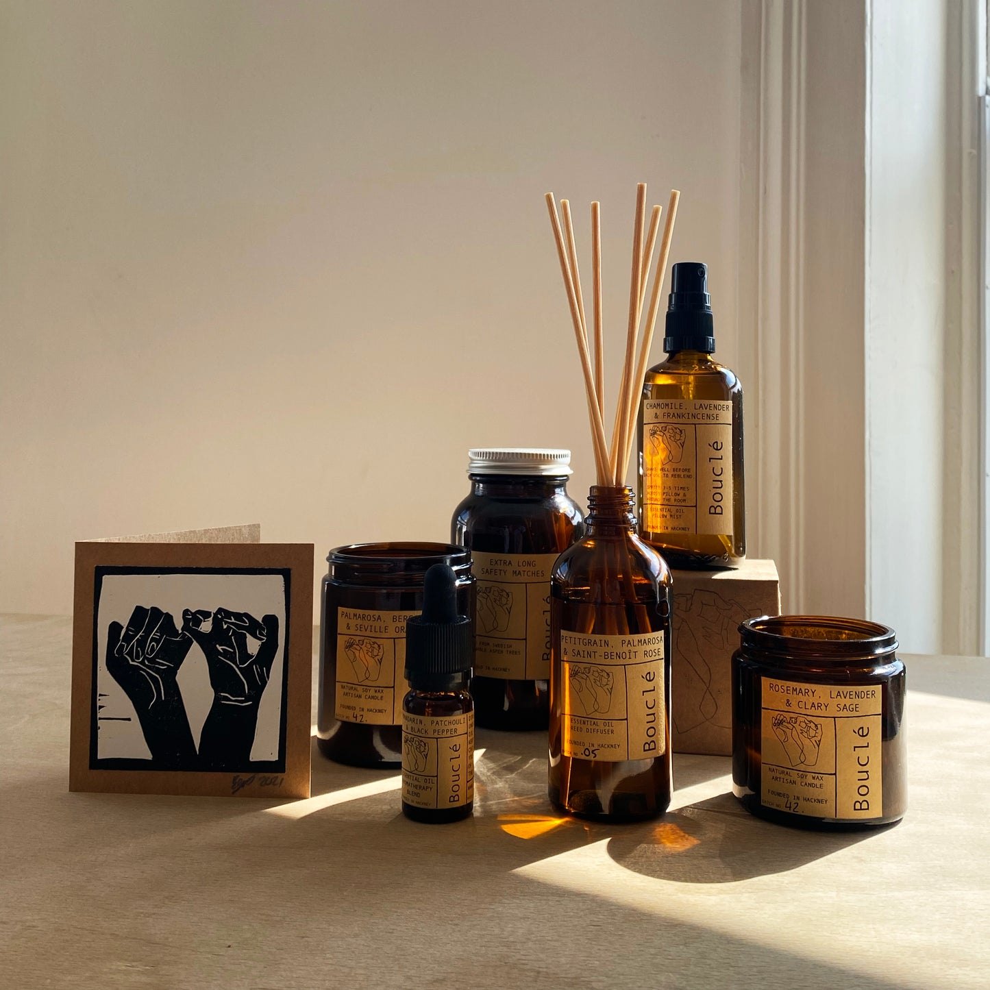 Bouclé London essential oil home fragrance including soy candle, bath salts, pillow spray and essential oil blend along side a hand printed card