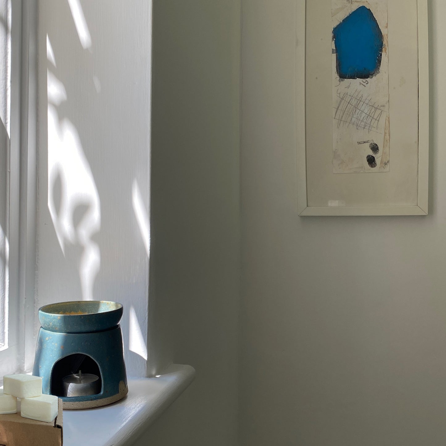 Bouclé London teal ceramic oil burner sitting in a minimal home alongside luxury wax melts made in east london and brighton